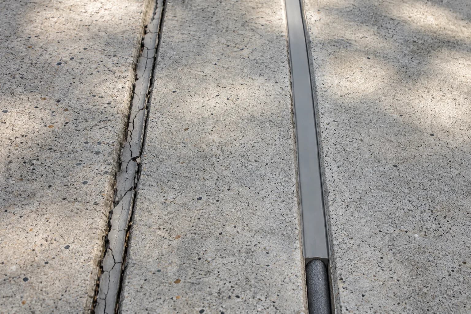 Concrete joints with failed old sealant beside a freshly sealed joint