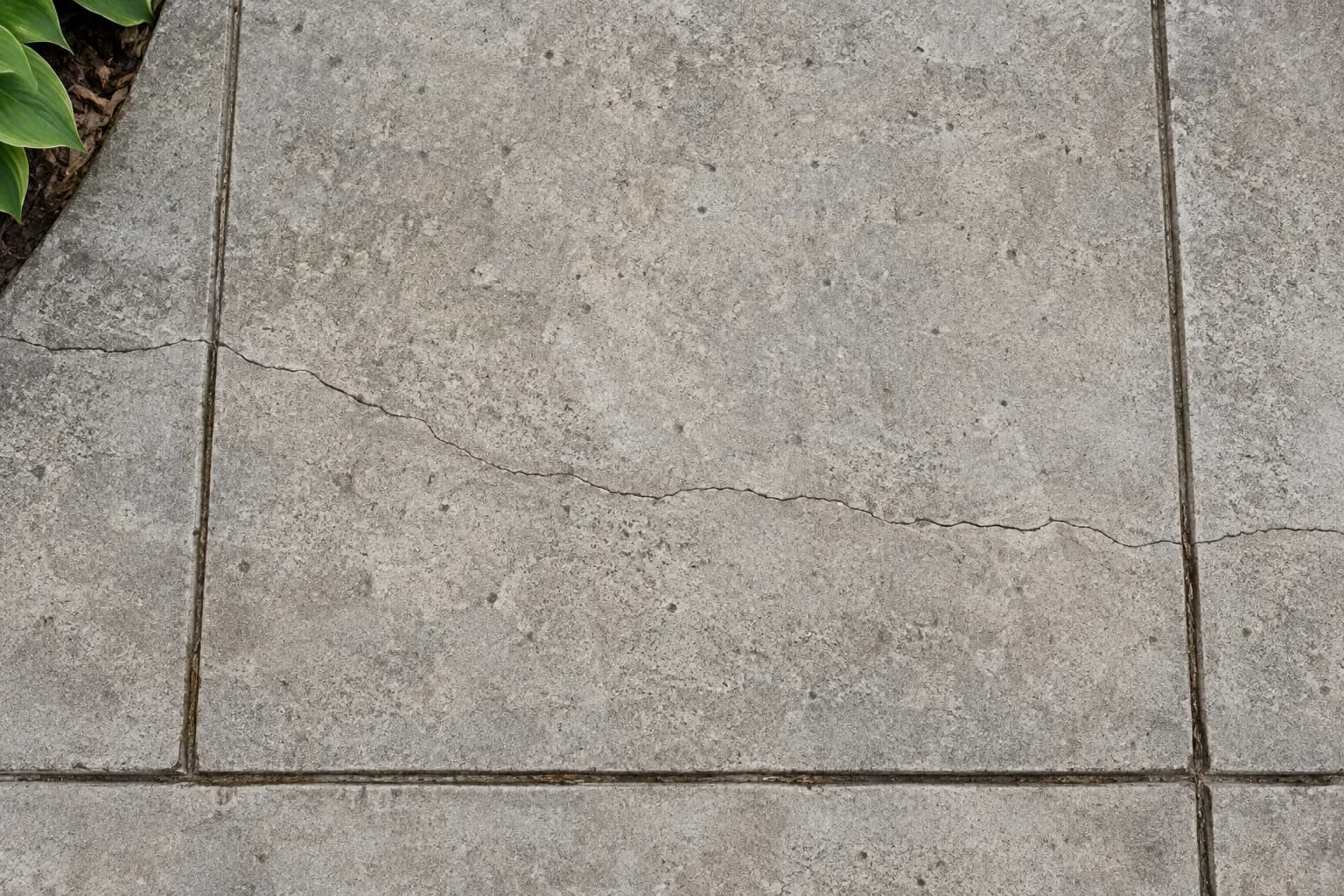Hairline crack crossing a concrete patio between two control joints